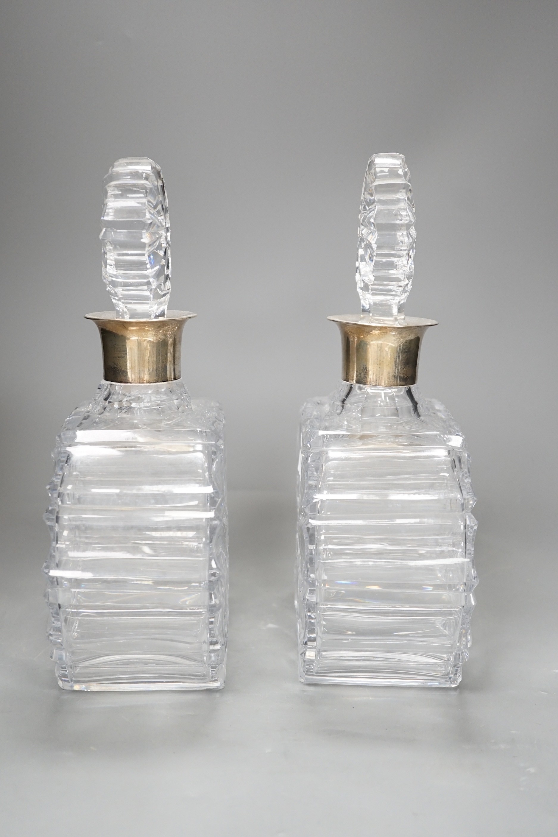 A pair of silver collared cut glass decanters. 27cm high.